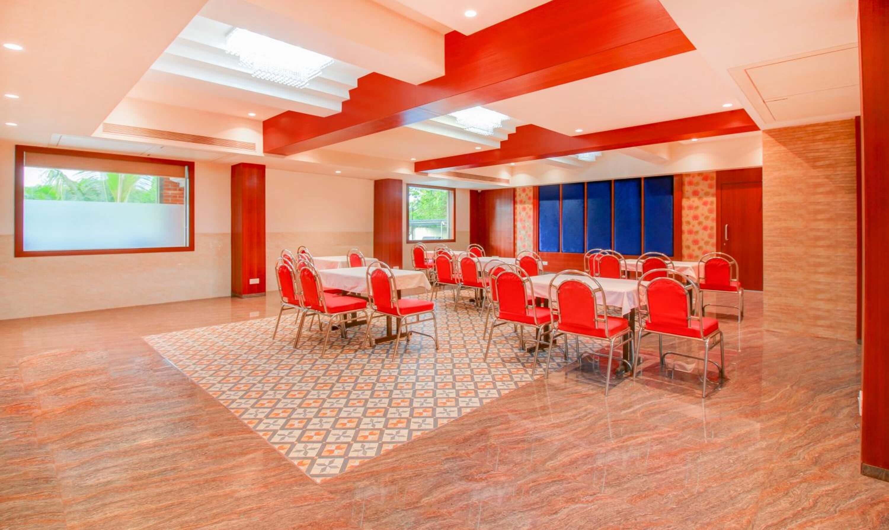 Une salle de conférence avec des chaises et des tables rouges, de grandes fenêtres et un tapis à motifs.