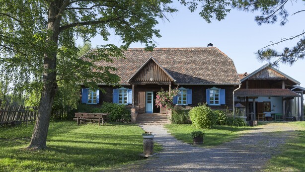 Una casa de madera tradicional con camino de grava, un banco de madera y una maceta.