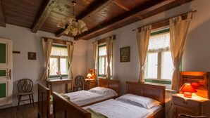 Una habitación con dos camas de madera, un escritorio, una silla y una lámpara.