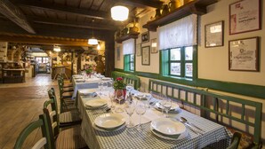 Un restaurante con manteles a cuadros, sillas tapizadas en verde y diplomas enmarcados en la pared.