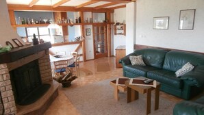 Una sala de estar con chimenea, sofá de cuero verde, mesa de centro de madera y un comedor con sillas y una mesa.