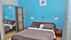 A bedroom with a bed, a wardrobe, a nightstand, and a wall-mounted light fixture. - Hôtel - Y (Douala)
