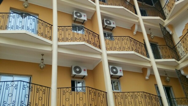 A multi-story hotel with balconies, air conditioning units, and a sign indicating it is a hotel. - Hôtel - Y (Douala)