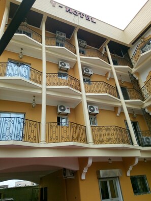 A multi-story hotel with balconies, air conditioning units, and a sign indicating it is a hotel. - Hôtel - Y (Douala)