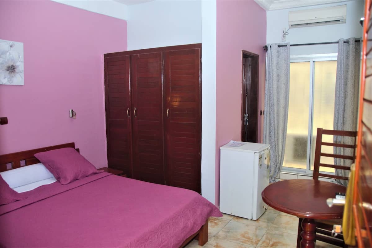 Un dormitorio con cama, armario, una mesita y una silla.