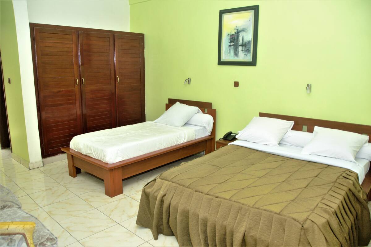 Una habitación con dos camas, un armario de madera y un cuadro en la pared.