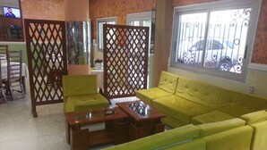 A living room with a yellow sofa, a wooden coffee table, and a glass-top table. - Hôtel - Y (Douala)