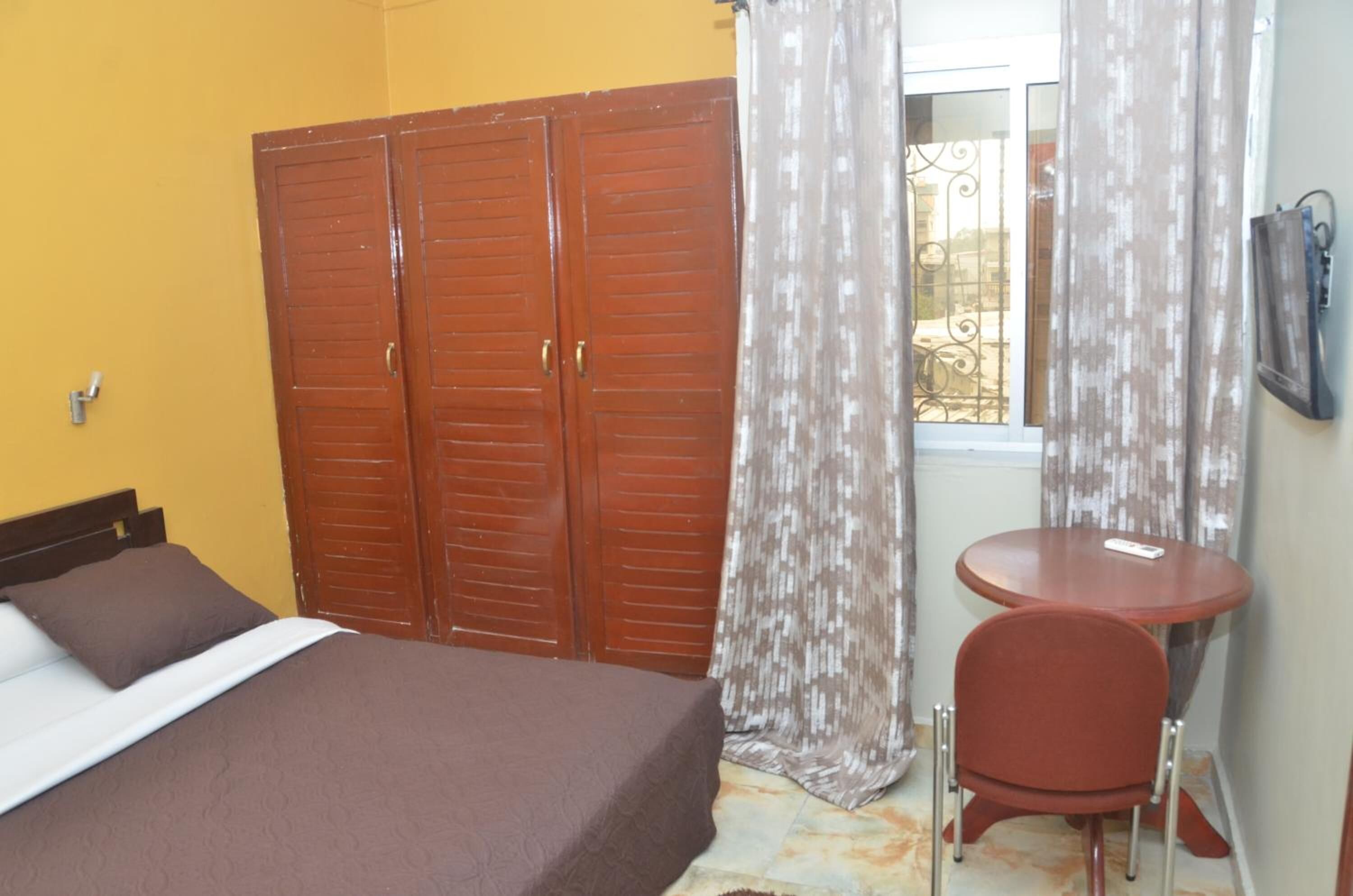 A bedroom with a bed, a wardrobe, a small table, and a chair.