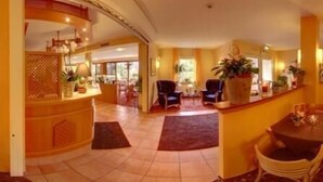 A hotel lobby with a reception desk, seating area, and a view of the outside. - Montana Senden Münster (Senden)