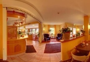 Un vestíbulo de hotel con mostrador de recepción, zona de estar y vistas al exterior.