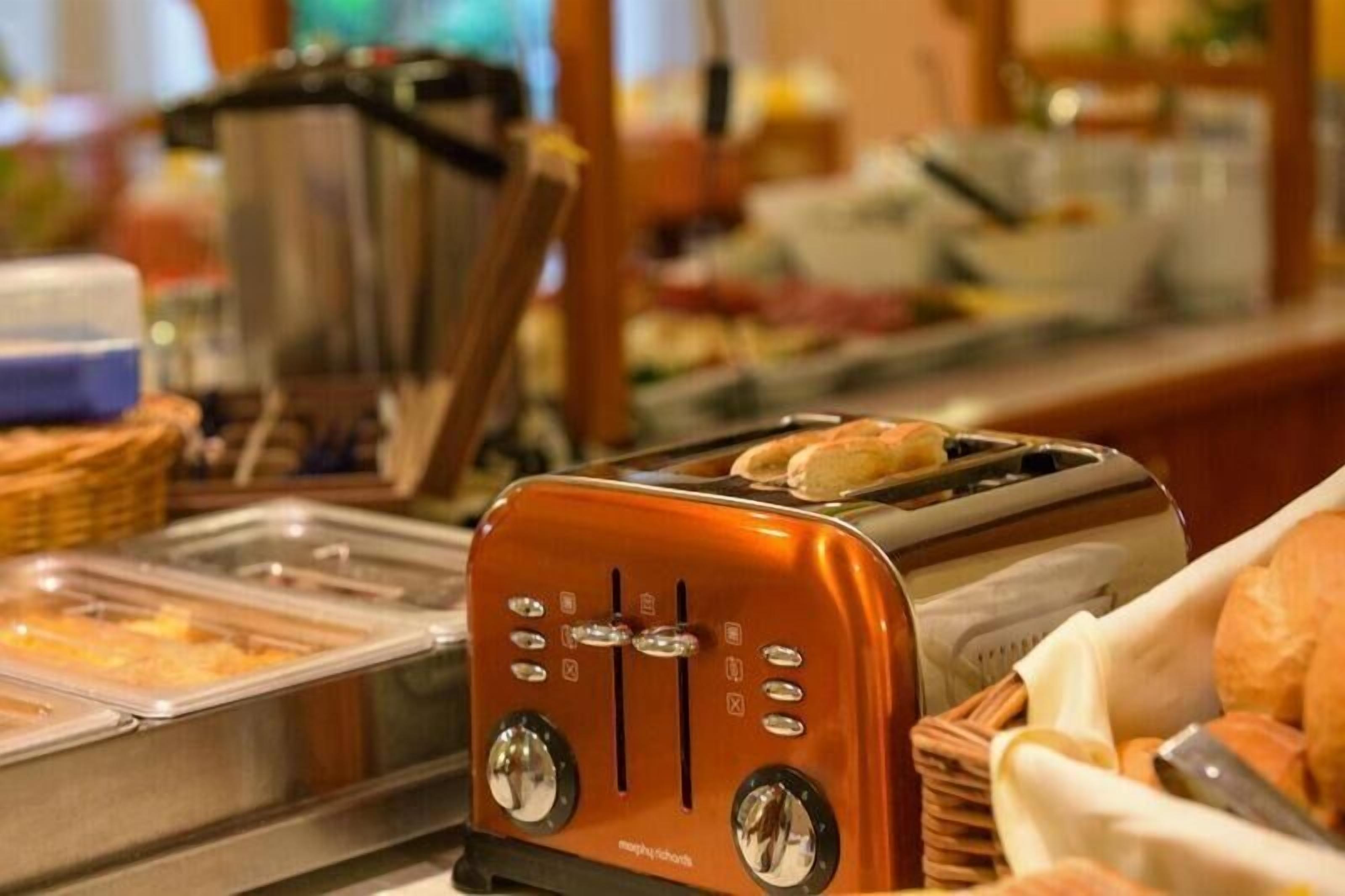 A buffet area with a toaster and various food items.
