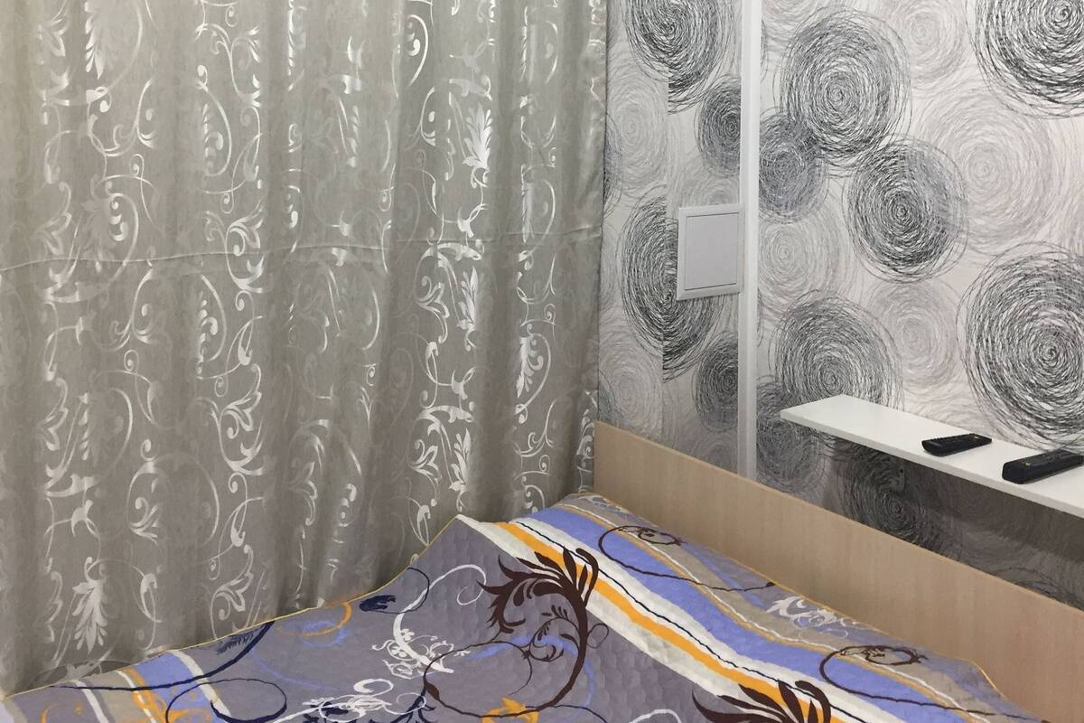 Relax in a stylish room with a comfortable bed, bedside table, and floral-patterned curtains.