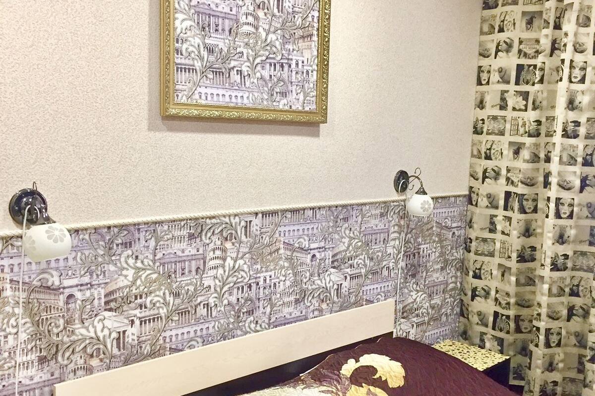 Classic hotel room with a patterned bedspread, decorative headboard, and framed picture on the wall.