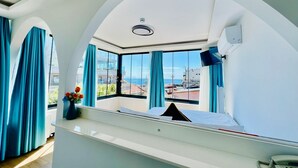 A modern hotel room with a large arched window, a bed, a bedside table, and a telephone. - Apex Hotel (Istanbul)