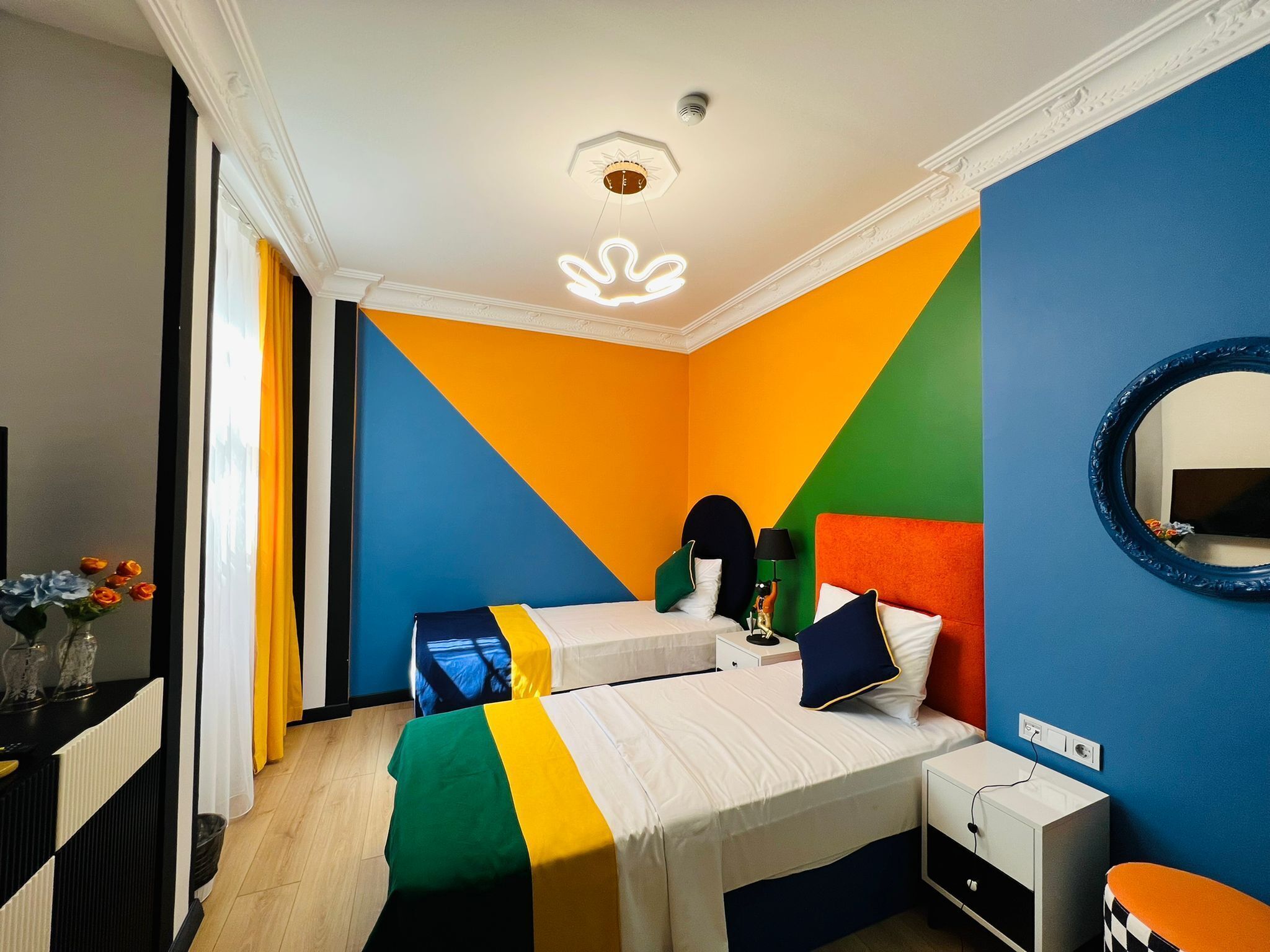 Ein Zimmer mit zwei Betten, einem Spiegel, einem Nachttisch und einer Kommode.
