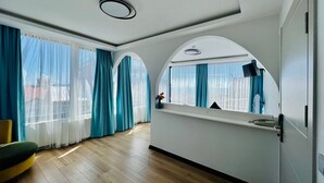 A modern room with wooden flooring, a large window with curtains, a mirror, and a desk with a chair. - Apex Hotel (Istanbul)