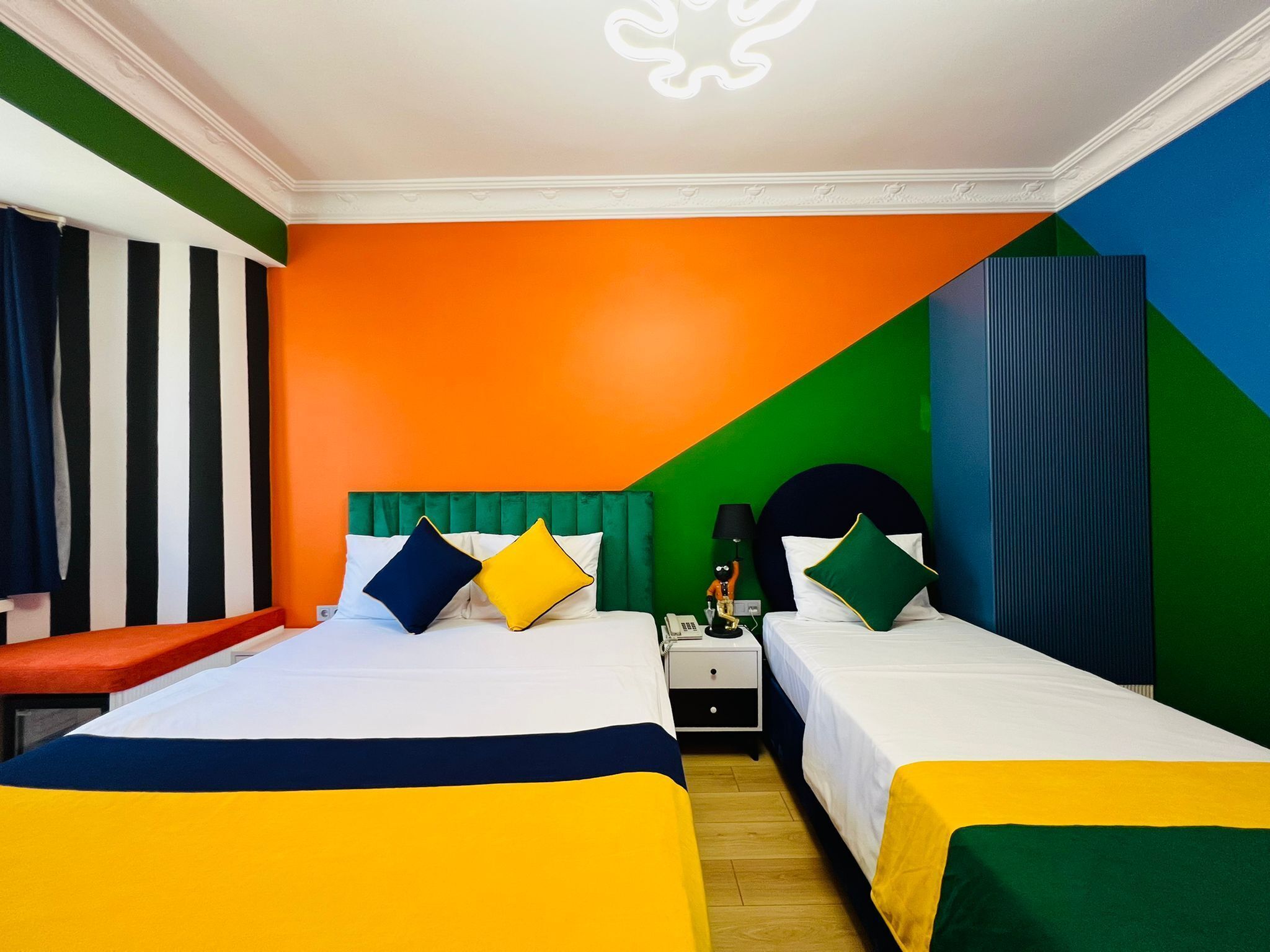 Habitación de hotel con dos camas, una mesita de noche y una cortina a rayas.
