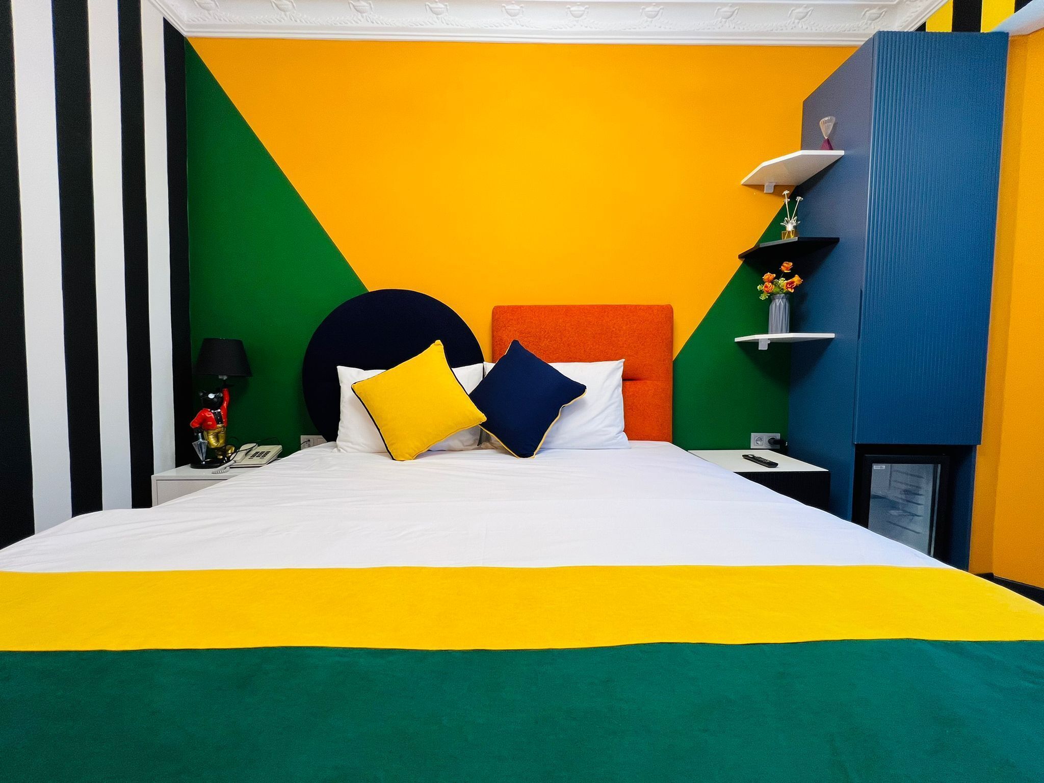 A bed with white bedding, a yellow pillow, and a blue pillow.