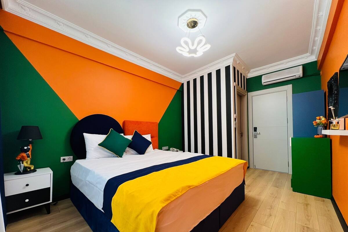 A modern bedroom with a bed, nightstand, and a wall with vertical stripes.