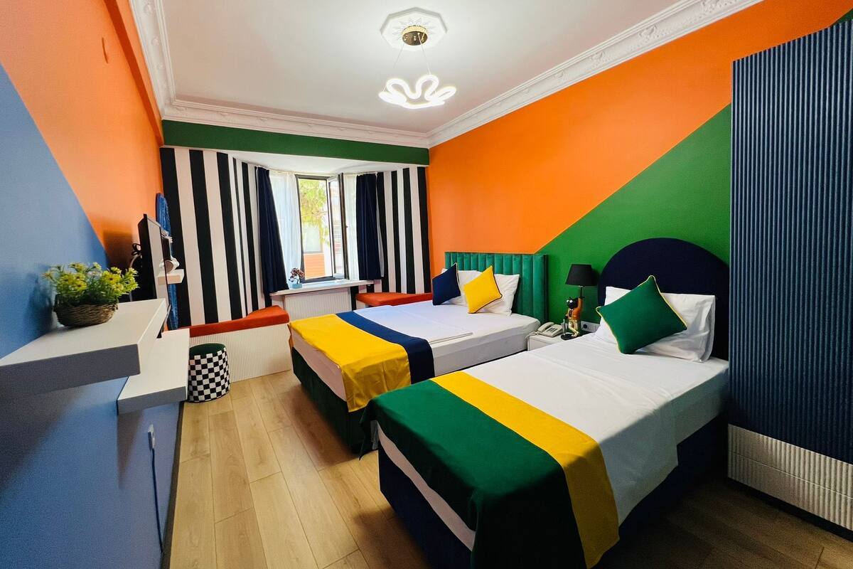 A room with two beds, a desk, and a window with curtains.