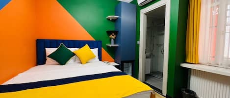 Una habitación luminosa y colorida con cama, ducha y radiador.