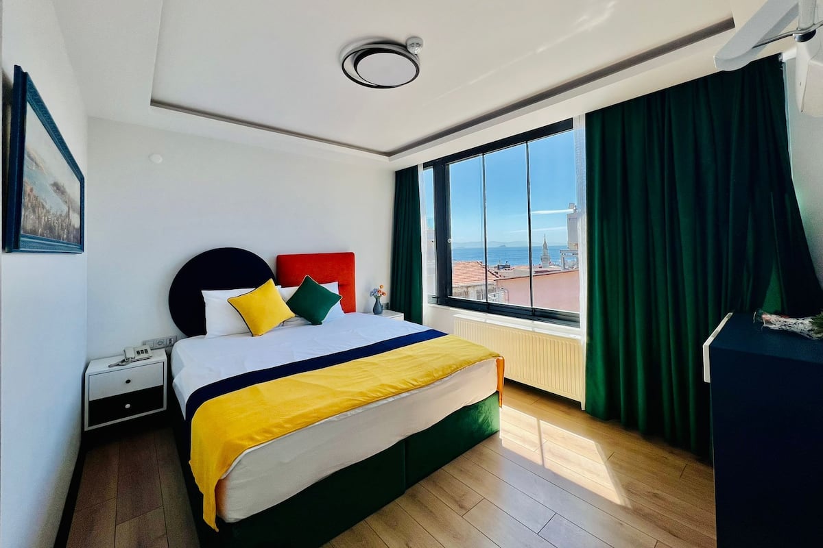A hotel room with a bed, a nightstand, a window with a view, and a ceiling light.
