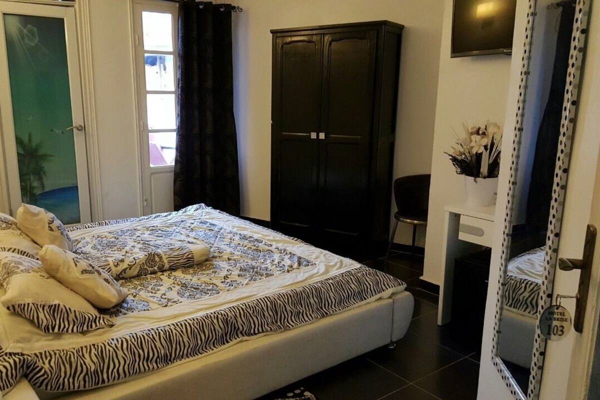 A bedroom with a bed, a wardrobe, a TV, and a bathroom door.