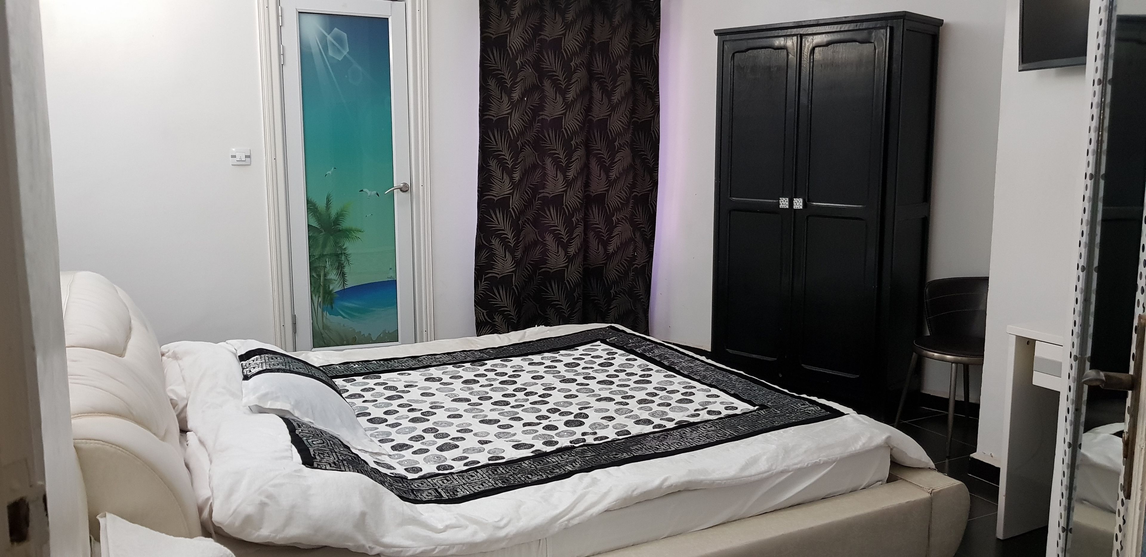 A bedroom with a bed, a wardrobe, and a view of the outside through a glass door.