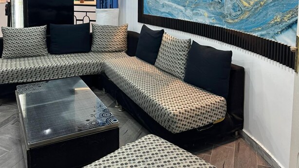 A modern living room with a sectional sofa, a coffee table, and a large abstract painting on the wall. - Hôtel La Brise (Ain El Turk)
