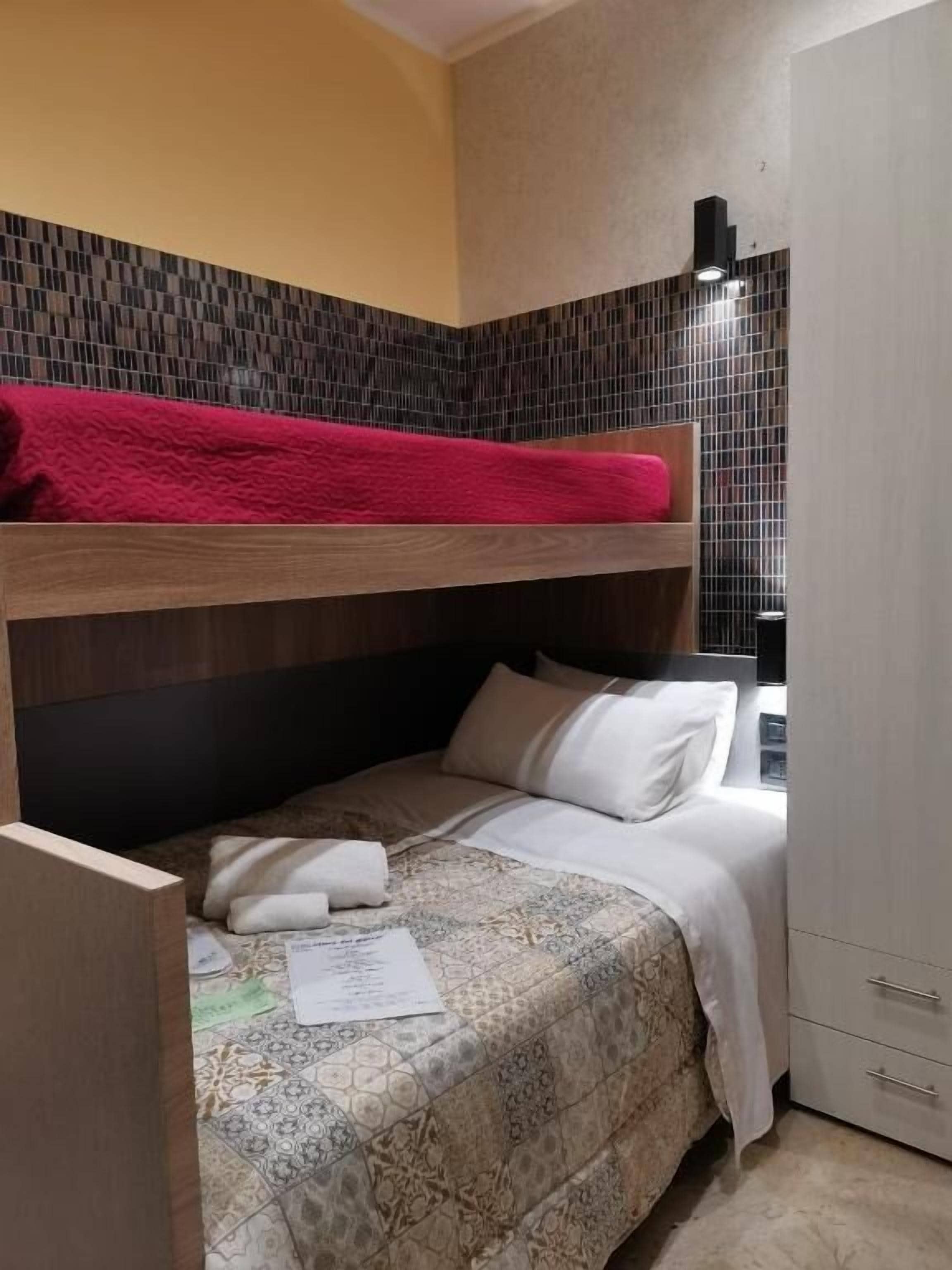 Un dormitorio con literas, una cama individual, un armario y un muro con azulejos.