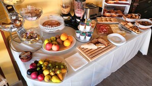 Een buffet met diverse gerechten, waaronder fruit, brood en gebak.