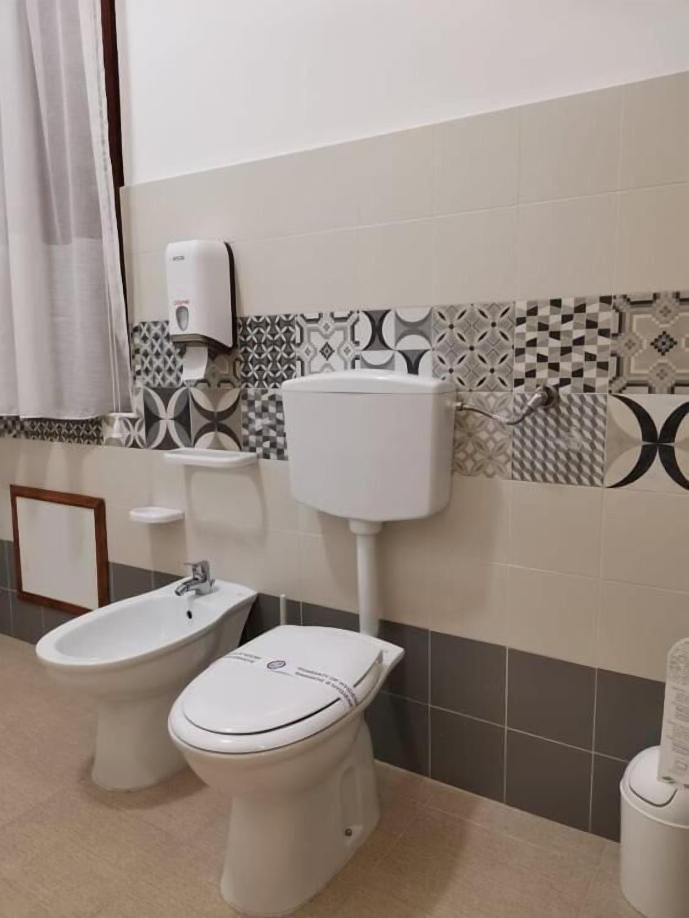 Une salle de bain équipée d’un bidet, de toilettes et d’un sèche-mains fixé au mur.