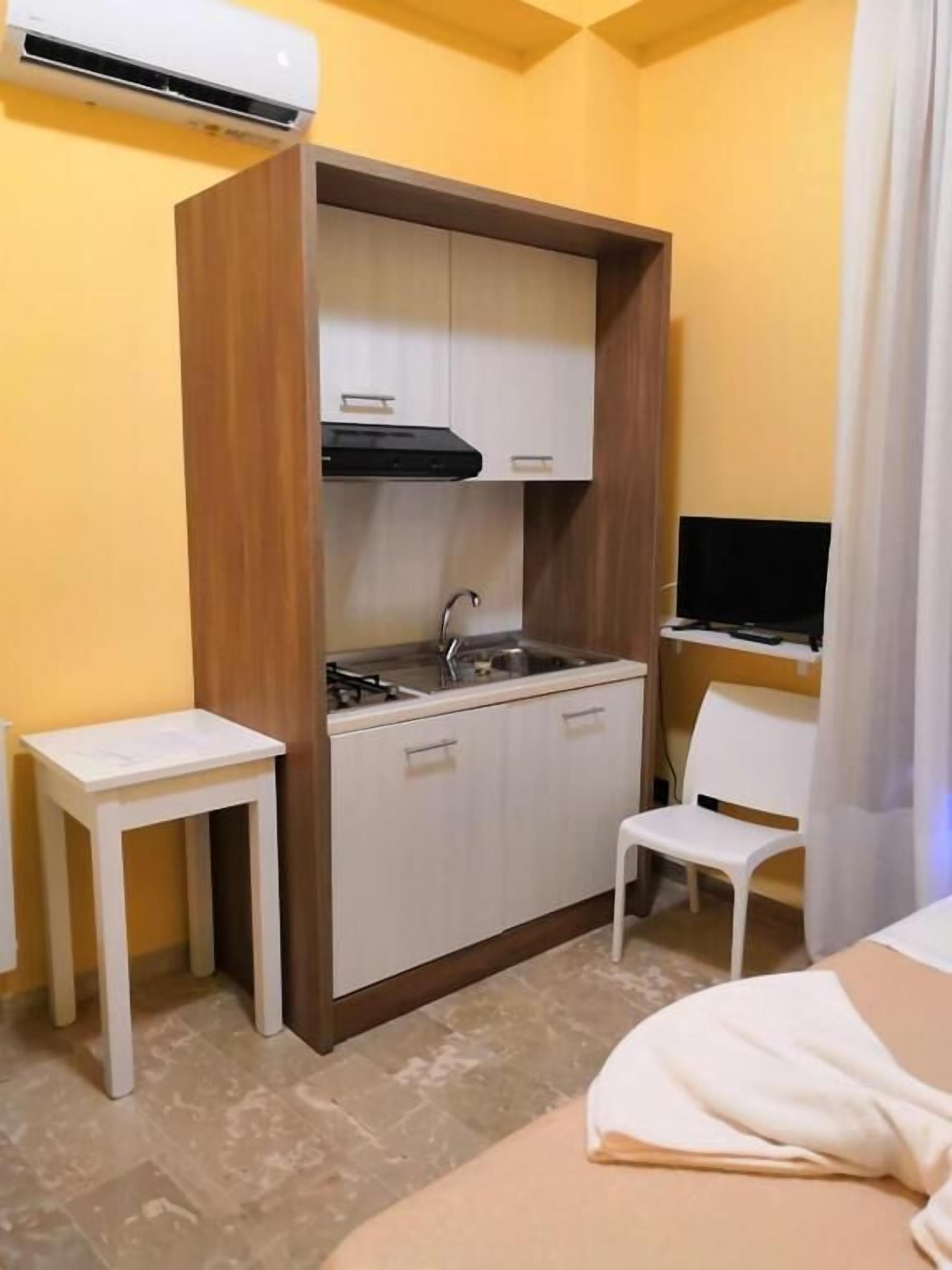 A compact kitchenette with a sink, cabinets, and a small table.