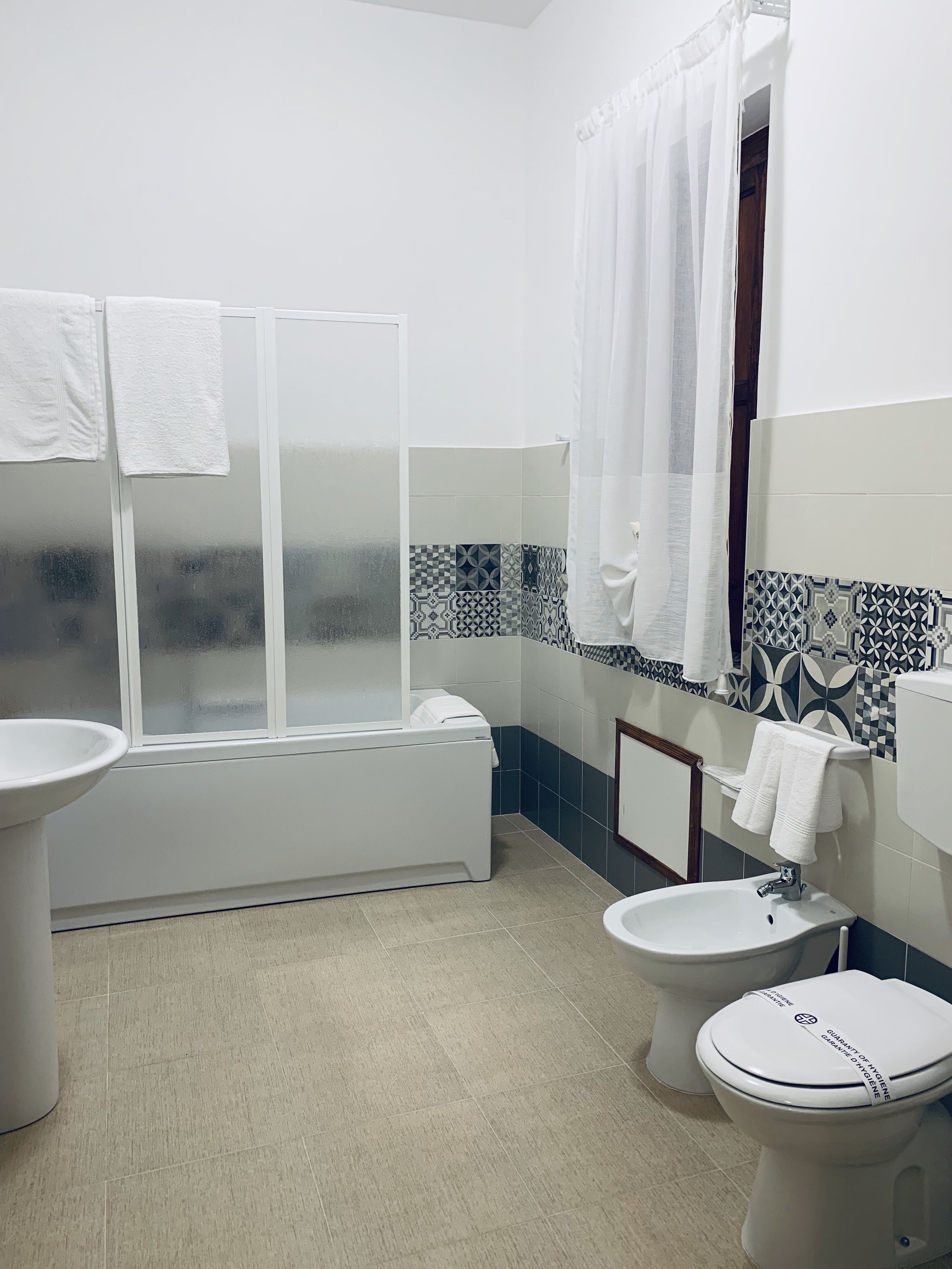 A bathroom with a bathtub, two toilets, a sink, and a shower curtain.