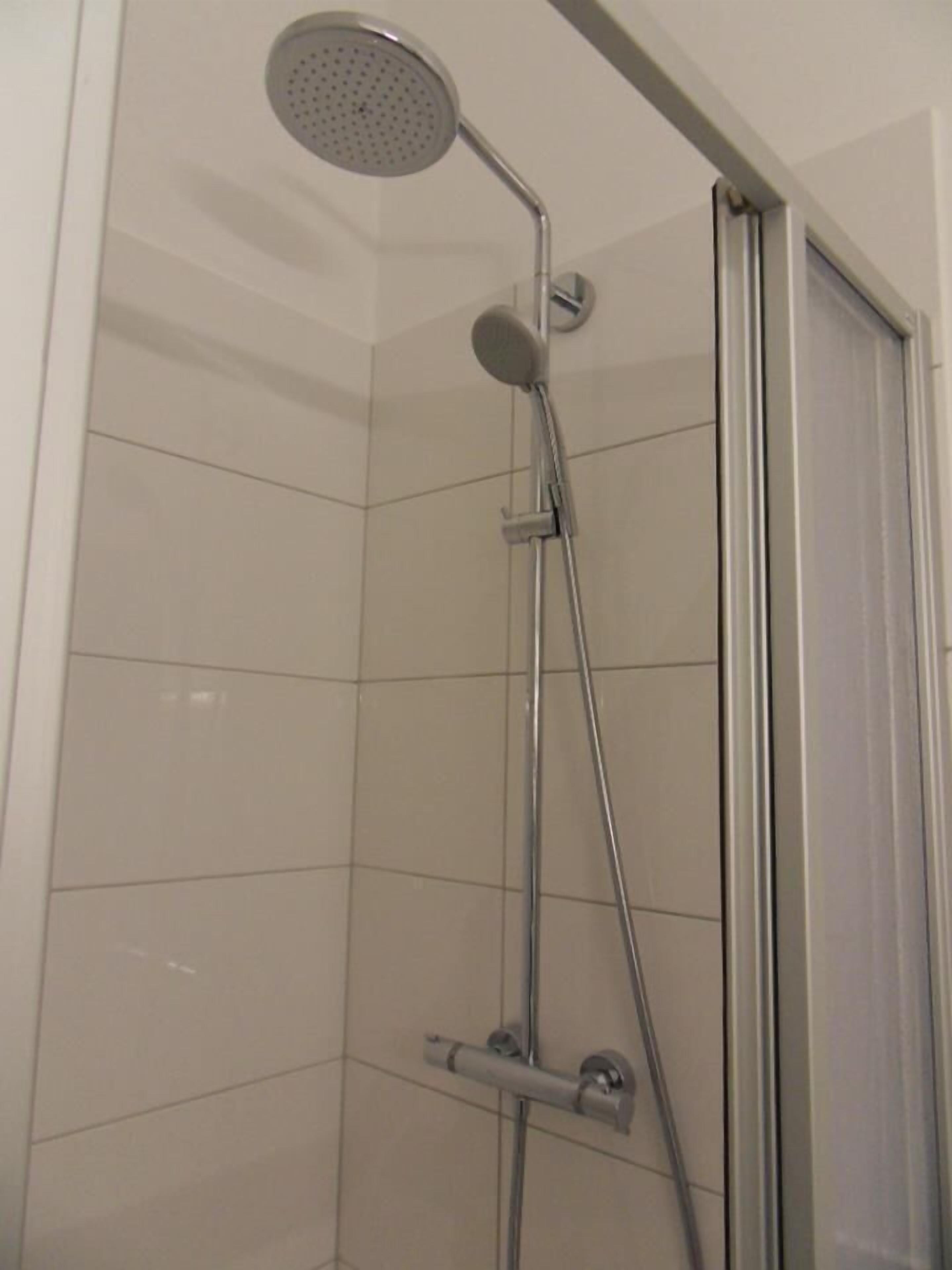 Ducha con cabezal de ducha de mano y grifo empotrado.