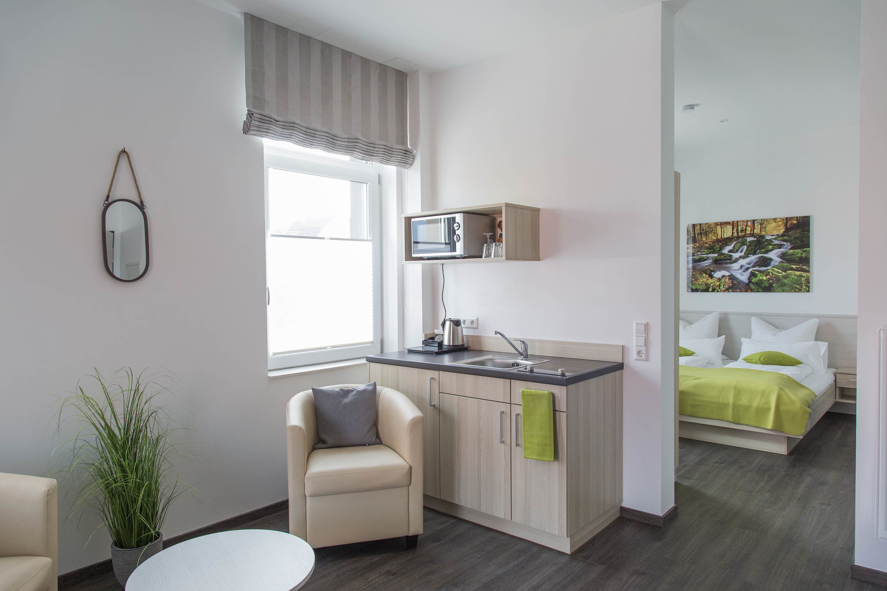 A modern, compact living space with a kitchenette, a dining area, and a bedroom.