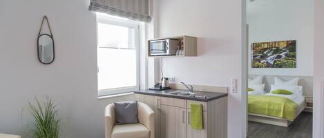A modern, compact living space with a kitchenette, a dining area, and a bedroom.
