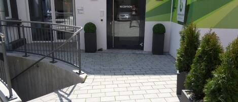 A reception area with a glass door, a staircase, and potted plants.