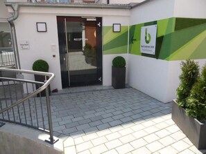 A reception area with a glass door, a key box, and a sign indicating 'best business building'. - Best Business Bühl - Boardinghouse (Bühl)