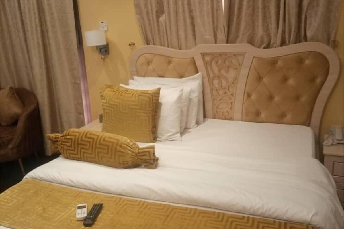 Quarto de hotel com cama, cortinas, uma cadeira e ar condicionado.