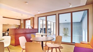 Un interior moderno con comedor, cocina y ventanas amplias.
