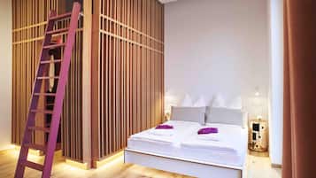 Ein modernes Hotelzimmer mit einer Wand aus Holzlamellen, einer Holzleiter, einem Doppelbett mit weißen Leinen und einem Nachttisch mit Lampe.