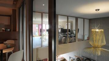 A modern interior with a dining area, a workspace with computers, and a music stand with instruments.