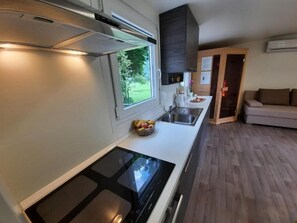Une cuisine moderne dotée d’une cuisinière intégrée, d’une fenêtre et offrant une vue sur l’extérieur.