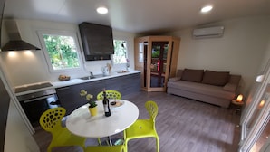 A modern kitchen with a dining area, a sofa, and a view of the outdoors. -  Apartment Zonir with sauna (Kobarid)