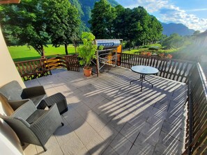 A terrace with wicker furniture, a potted plant, and a table. -  Apartment Zonir with sauna (Kobarid)