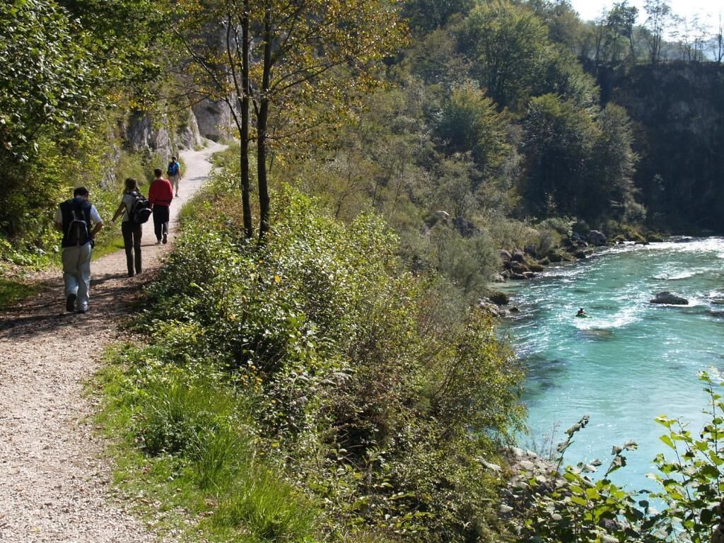 Un sentier de gravier longeant une rivière, avec des randonneurs.