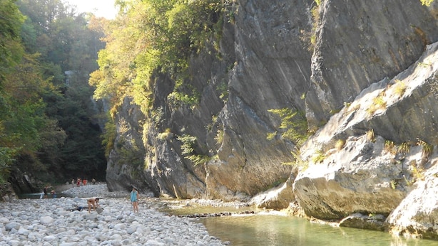 A rocky riverbank with clear water, surrounded by cliffs and trees. -  Apartment Zonir with sauna (Kobarid)