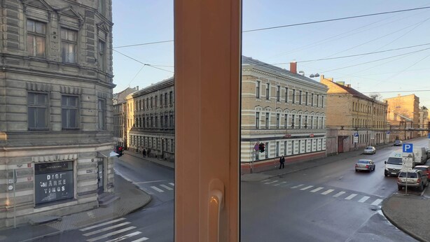Una strada con edifici, un attraversamento pedonale e auto parcheggiate.
