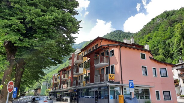 A multi-story building with balconies, a parking sign, and a stop sign. - Apartment Honey Bee with Sauna (Kobarid)